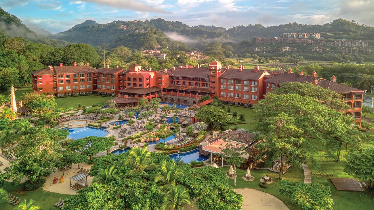 Aerial of exterior and pool at Marriott Vacation Club at Los Suenos resort timeshare with mist-shrouded mountains in distance